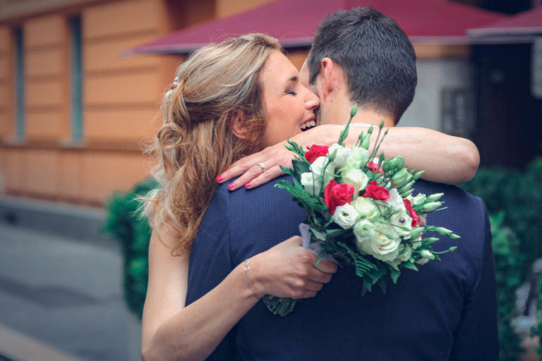 Câlin des mariés avant leur cérémonie civil avec le beau bouquet de la mariée en premier plan.