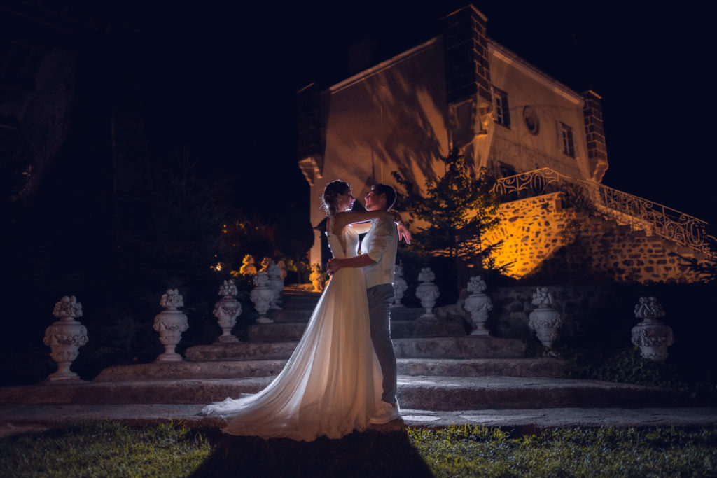 Les mariés se regardent face à face de nuit devant un château, la robe de mariée et bien mise en valeur