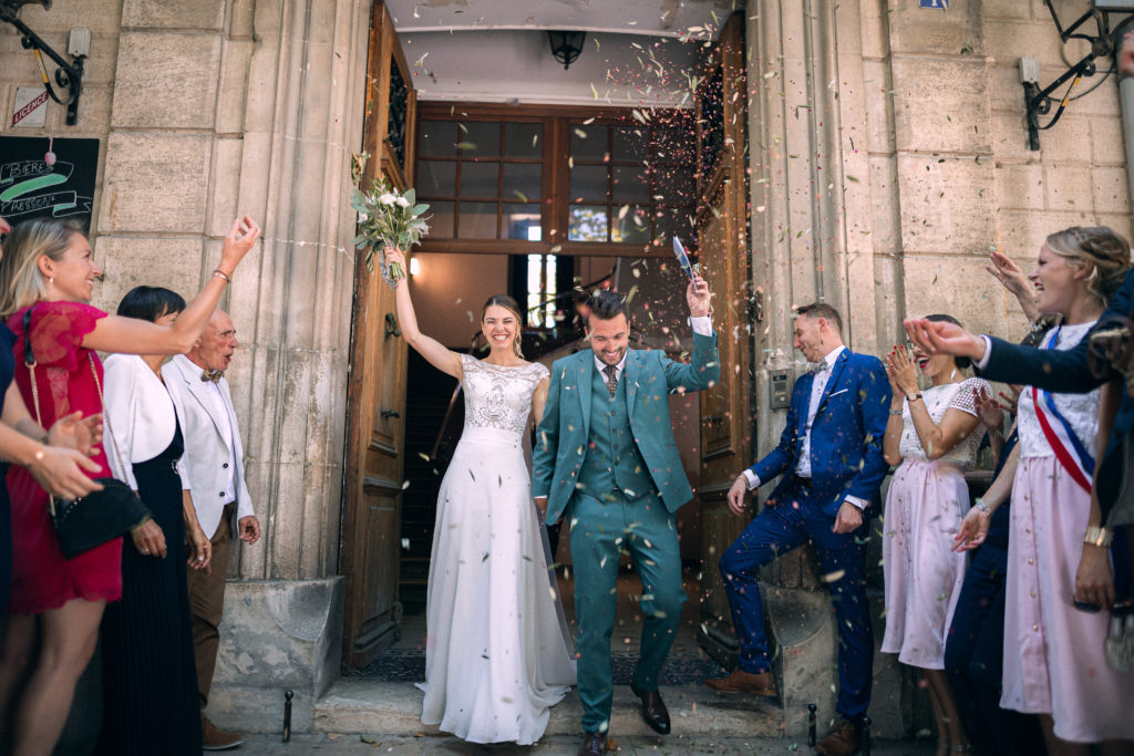 Les mariés sortent de la mairie sous les pétales de fleurs et les feuilles d'olivier lancés par les invités.