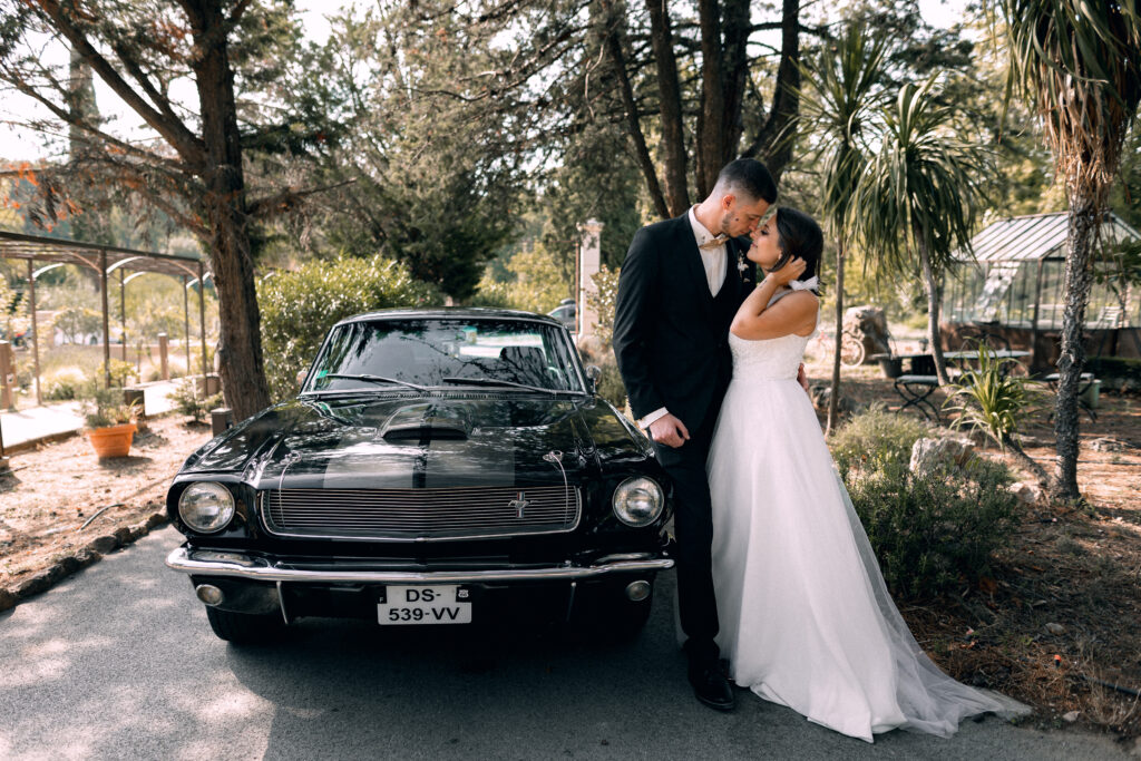 Les mariés s'embrassent devant leur voiture, une Ford mustang louée à l'occasion de leur mariage.