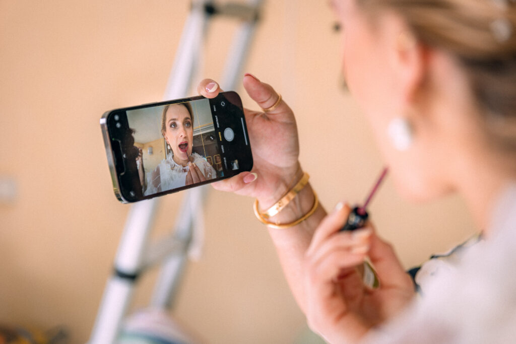 La mariée se maquille à l'aide de son téléphone pendant ses préparatifs.