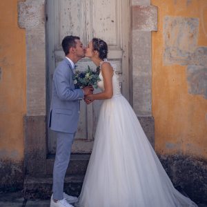 Mariés qui s'embrassent devant une jolie porte d'époque dans la ville pour leur séance couple le jour de leur mariage.